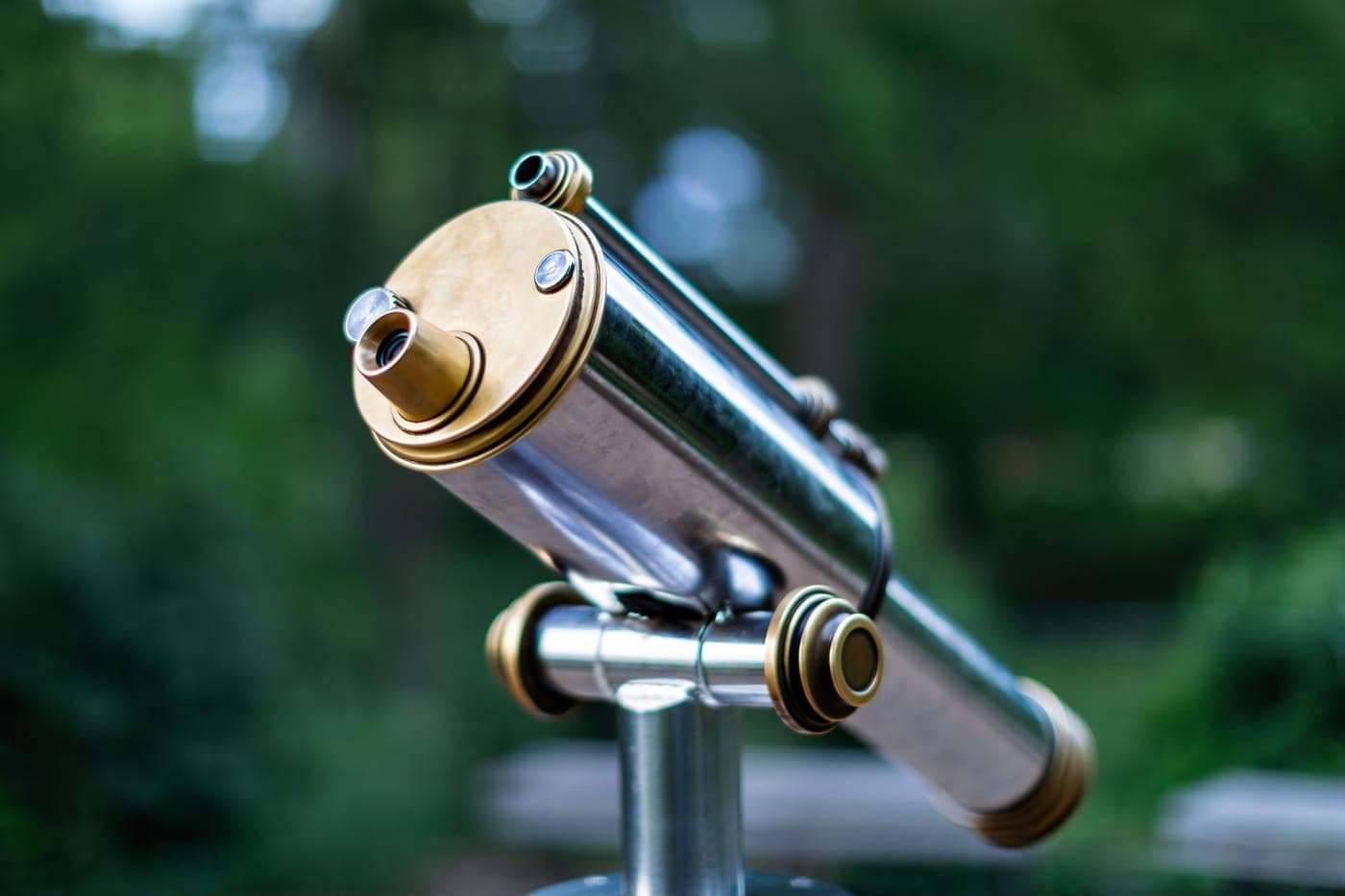 A classic brass-finished outdoor telescope against a blurred background